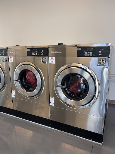 A row of spotless stainless-steel Speed Queen front-load washers inside Main Street Laundry
